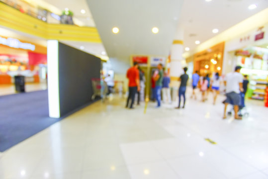 Blur image of people queing at ATM Machine in shopping mall.