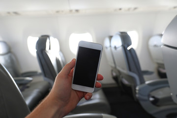 The man using mobile phone on the airplane while traveling