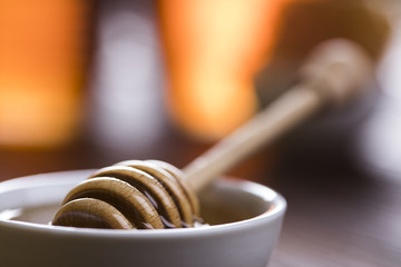 Honey in jar with honey dipper on wooden background 