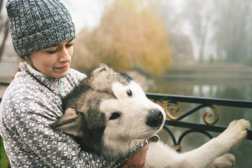 Image of young girl hug her dog, alaskan malamute, outdoor