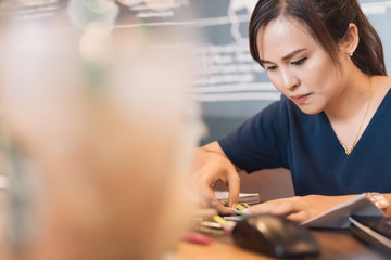 Young Asian woman administrative manager working with financial documentation and financial reports in online database checking in selective focus.