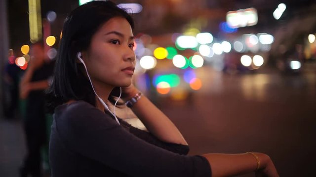 Asian Girl listening music on night street near bus stop 4k UHD (3840x2160)
