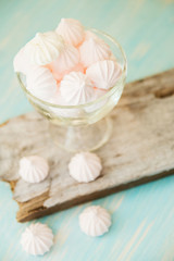 Some delicious pink macarons in a glass jar on a white wooden table with a robin egg blue background. Vintage Style.