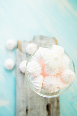 Some delicious pink macarons in a glass jar on a white wooden table with a robin egg blue background. Vintage Style.