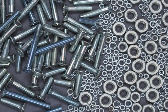 A Bunch Of Screw Nuts And Bolts On A Gray Background