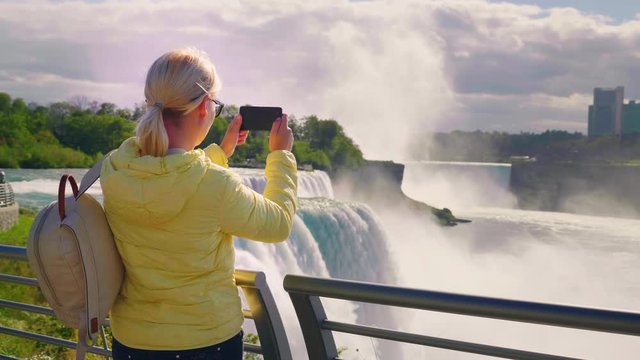 A woman tourist takes pictures of the famous Niagara Falls in the USA