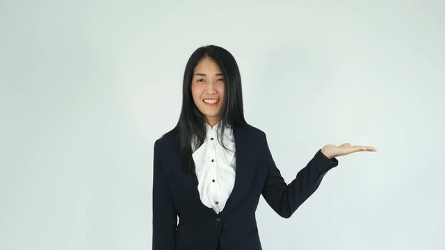 Closeup of young business woman with presenting something on her hand smiling at camera and showing at blank copy space