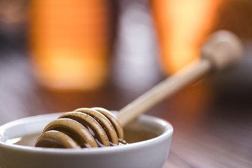 Honey in jar with honey dipper on wooden background 