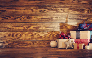 Fototapeta na wymiar Old wooden planks with christmas decoration. Brown background with gift boxes, candles, stars and snow