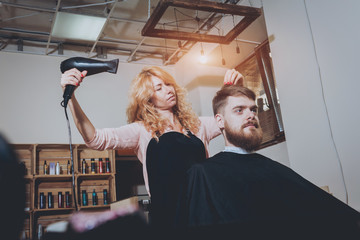 Master cuts hair and beard of men, hairdresser makes hairstyle for a young man. Hipsters