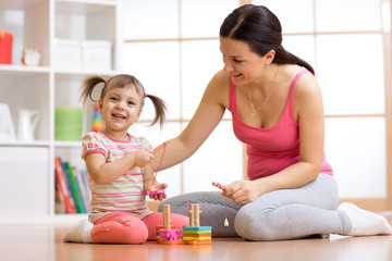 Cute woman and kid girl playing educational toys at home
