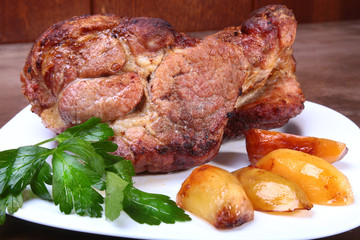 Juicy pork neck chops are grilled with potatoes on a white plate.