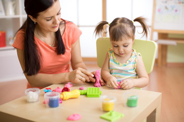 child girl and teacher play with color dough at home