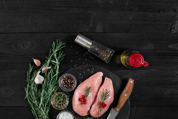 Raw chicken fillet with cooking ingredients on black slate table. Food background. Top view, copy space.