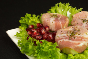 goat cheese with bacon on a frisee lettuce leaf with pomegranate as garnishing