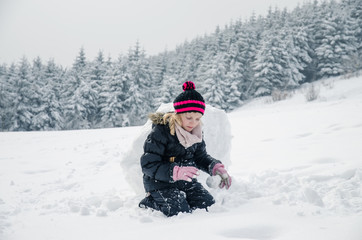 Fototapeta na wymiar little child building a snowman