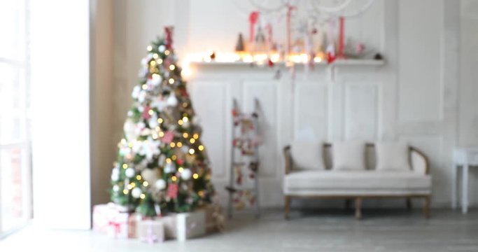 4K video footage of white room with Christmas and New Year interior decoration. Green tree decorated with toys and flashing garland