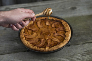 Homemade apple quince pie with wooden honey dipper on rustic background. Top view