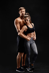 Sport, fitness, workout concept. Fit couple, strong muscular man and slim woman posing on a black background