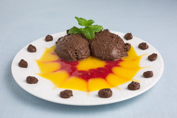 chocolate mousse on plate with pureed fruit in red and yellow