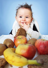 Fototapeta premium Cute Baby boy trying to decide what healthy food to eat first for breakfast on bright blue background