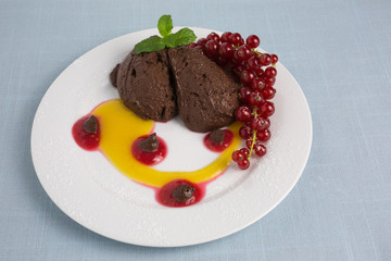 chocolate mousse on plate with pureed fruit in red and yellow