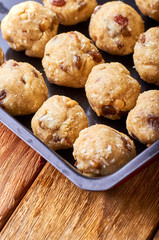 Traditional national Indian homemade sweets Rava ladoo. Oriental candies with own hands. Sweet delicious dessert with nuts and raisins. Dessert of milk powder on a baking sheet on a wooden table.