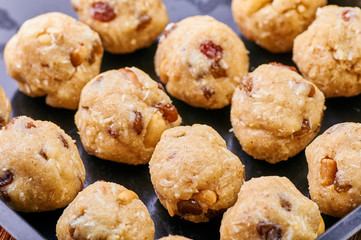 Traditional national Indian homemade sweets Rava ladoo. Oriental candies with own hands. Sweet delicious dessert with nuts and raisins. Dessert of milk powder on a baking sheet on a wooden table.
