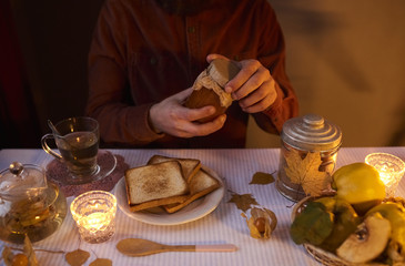 Man preparing to eat a sandwich with homemade jam with quinces an tea on table