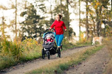 Fototapeta na wymiar Running mother with stroller enjoying motherhood at autumn sunset