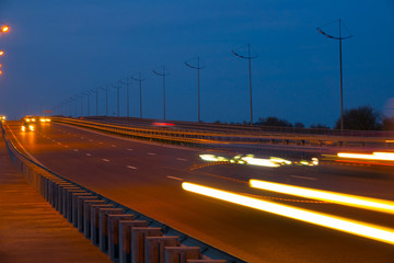 Highway traffic cars at night blured. Cars moving on road on bridge evening blurry.