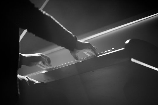 The pianist performs a musical work on the piano on stage