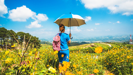 Asian women travel sleep relax. women hill tribe umbrella stand in the field of flowers. Thailand