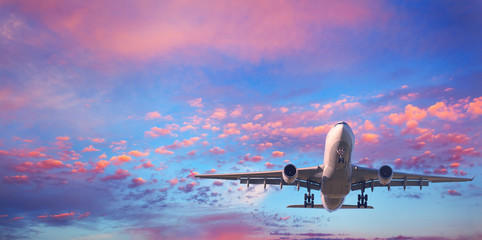 Landendes Flugzeug. Landschaft mit weißem Passagierflugzeug fliegt bei Sonnenuntergang in den blauen Himmel mit rosa Wolken. Reisehintergrund. Passagierflugzeug. Geschäftsreise. Passagierflugzeug. Privatjet