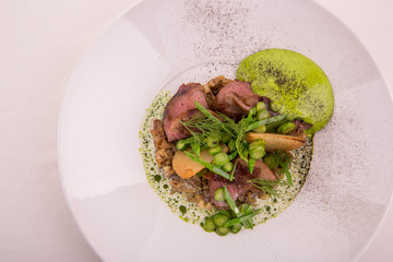 The fried beef tongue in sauce broth, is served with fried potatoes, cream from horse-radish and greens