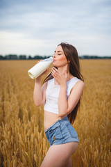 Beautiful woman is drinking milk in countryside
