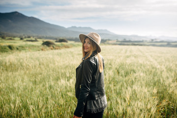 Beautiful smiling girl in a hat on a green field background