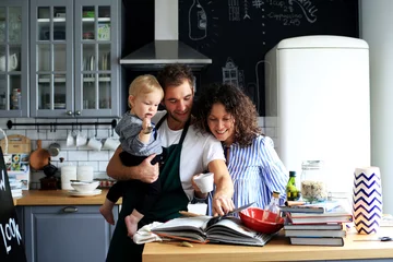 Selbstklebende Fototapeten Junge Familie, die das Mittagessen in der Küche zubereitet © Zarya Maxim