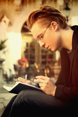 young man reading book in old Europe city (Education, training, development, knowledge concept)