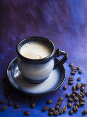 A cup of coffee and coffee beans on a beautiful blue background with space for text.