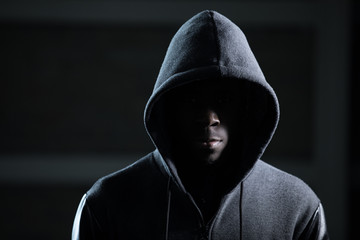 Mysterious african man with hood in darkness - obrazy, fototapety, plakaty
