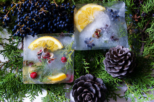 Ice with frozen oranges and berries, lying on coniferous branches.