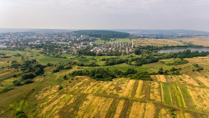 Obraz premium Aerial view of the summer countryside. A flight over a green field and town