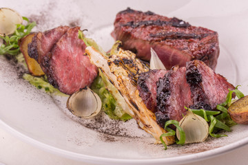 Beef and an edge, is served with cabbage a grill, the onions fried on a grill, fried potatoes with lettuce leaves in the Red Wine sauce