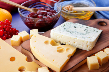 Different cheeses, lemon, pomegranate, mandarin, pears, berries, honey, jam, cheese with a mold on a wooden board in the style of pop art and retro style, Christmas cheese, festive dinner