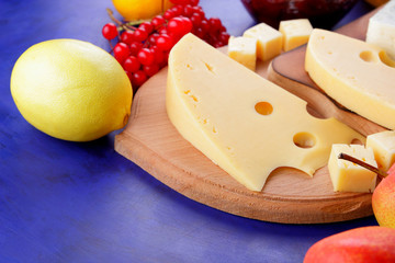 Different cheeses, lemon, pomegranate, mandarin, pears, berries, honey, jam, cheese with a mold on a wooden board in the style of pop art and retro style, Christmas cheese, festive dinner