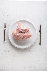 Top of view frozen turkey chicken on white plate with fork and knife