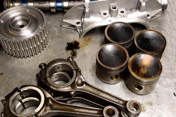 Car parts including piston, connecting rod and cam shaft on a metal table