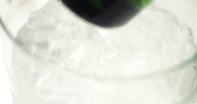 Close up video of taking a chilled bottle of sparkling wine out of a clear glass ice bucket on white, gray and golden background
