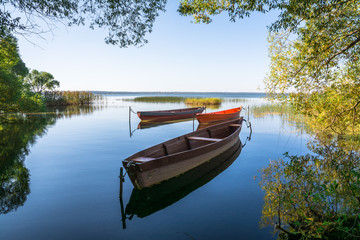 Naklejka na ściany i meble Boats on the water of the lake surrounded by trees